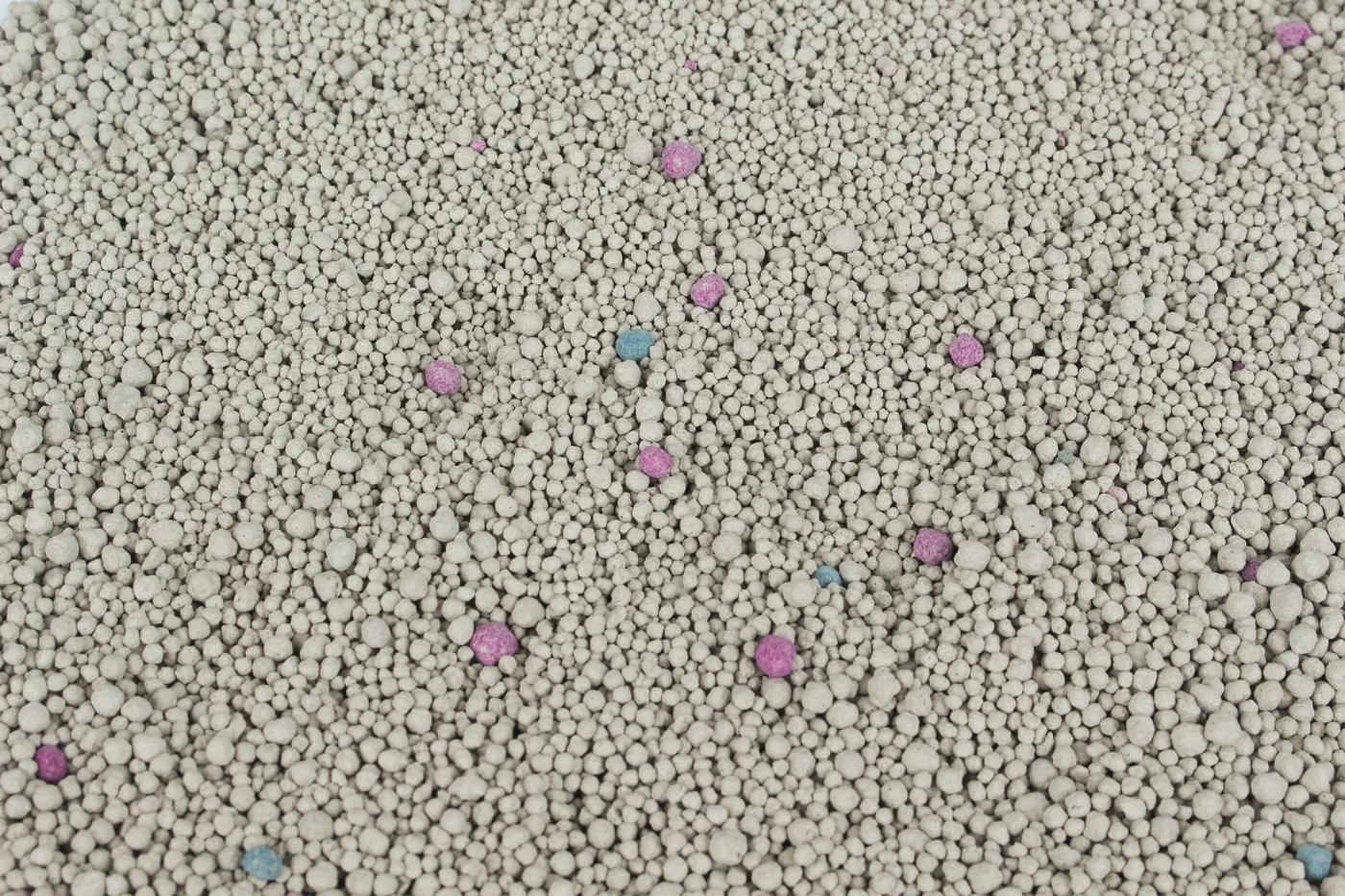 Close-up of grey round LINGSHUAI bentonite granules with scattered coloured granules